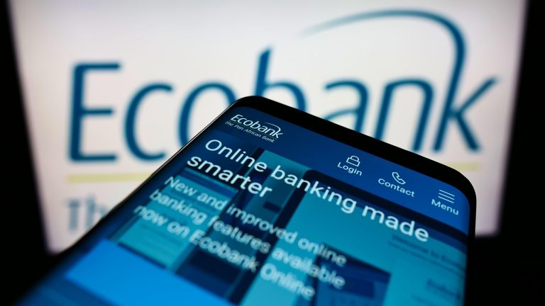 Cellphone with webpage of African bank Ecobank Transnational Inc. on screen in front of business logo. Focus on center of phone display