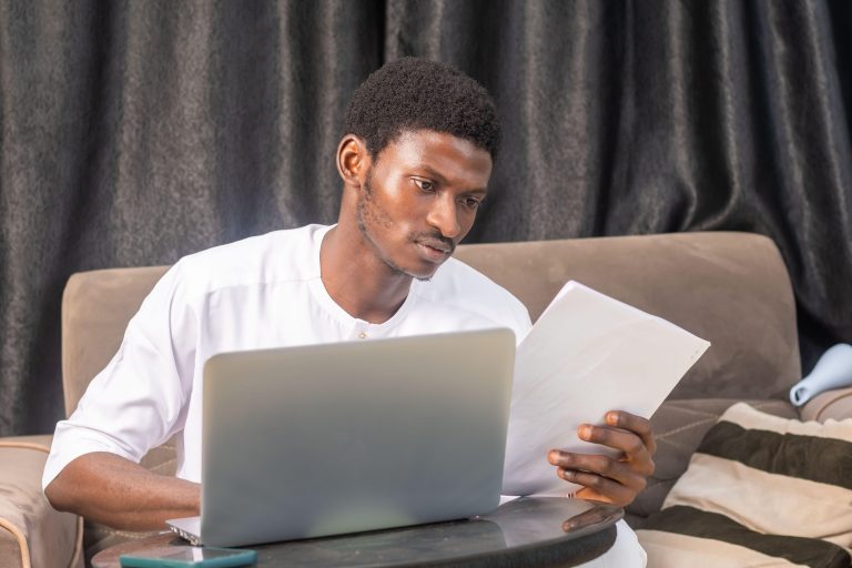 Satisfied smiling business man doing paperwork at home workplace. Entrepreneur reading financial reports, reading documents