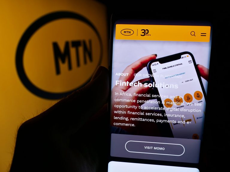 Person holding smartphone with webpage of South African telecommunications company MTN Group Limited with logo. Focus on center of phone display